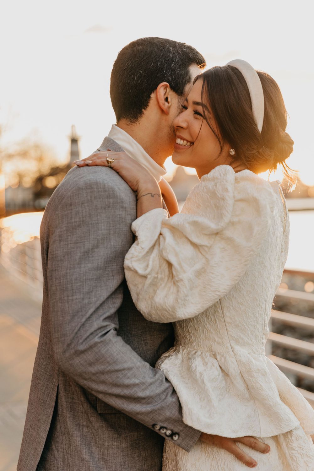 A tender embrace at sunset between a couple in formal wedding attire.