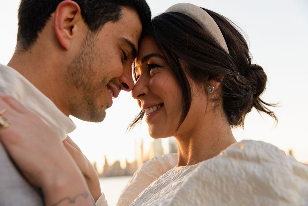 Intimate sunset portrait of couple sharing tender moment with city backdrop.