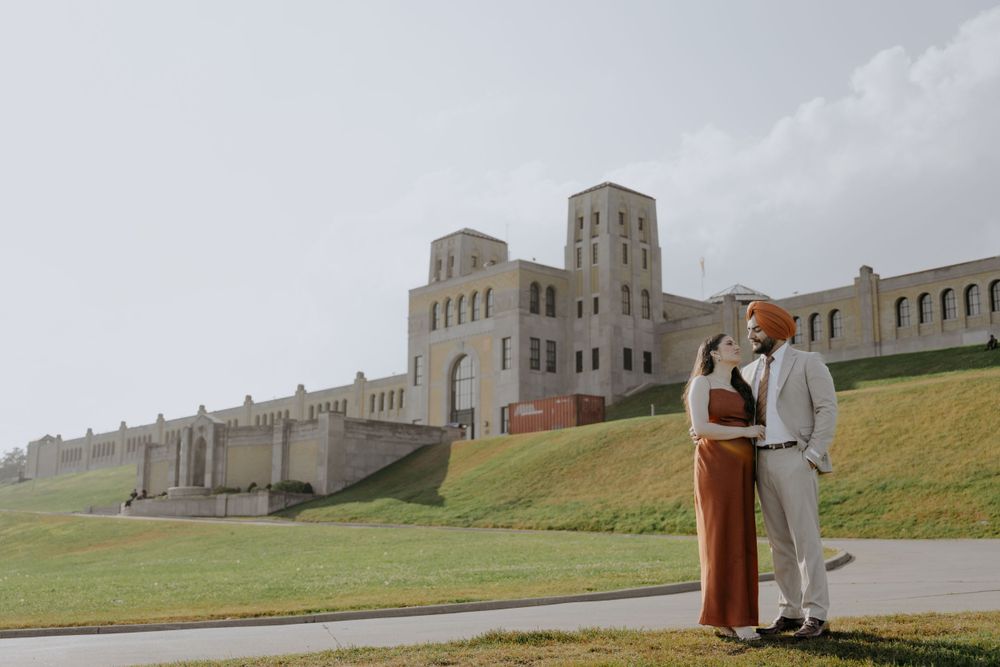 A couple posing in front of a majestic stone building with twin towers.
