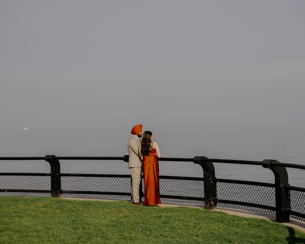 A couple standing by a railing overlooking a misty horizon at dusk.