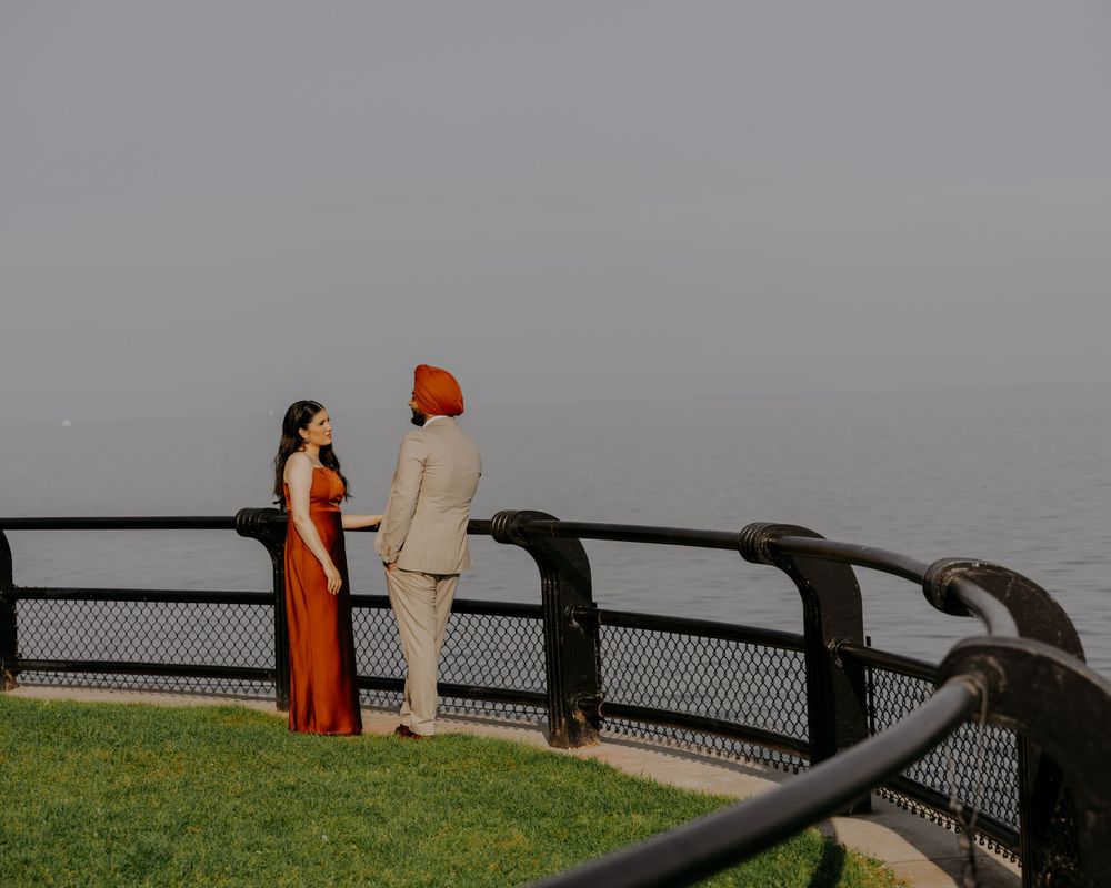 A couple enjoying the view from a curved waterfront railing on a cloudy day.