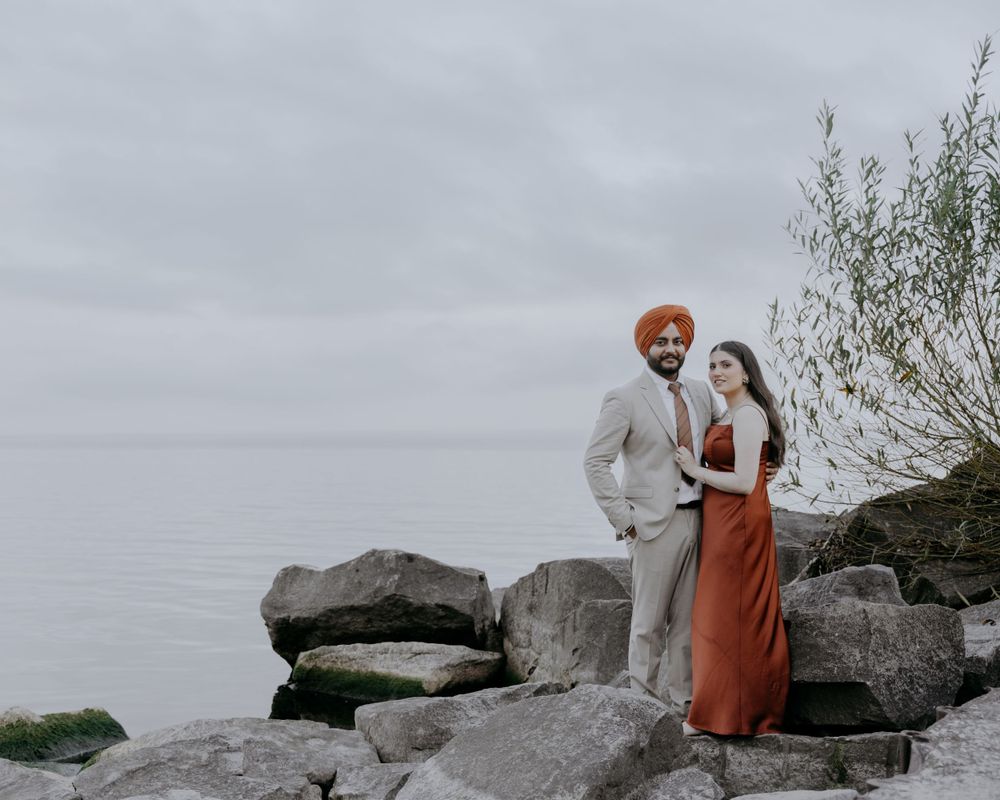 A couple poses together on rocky coastal terrain against a misty backdrop.