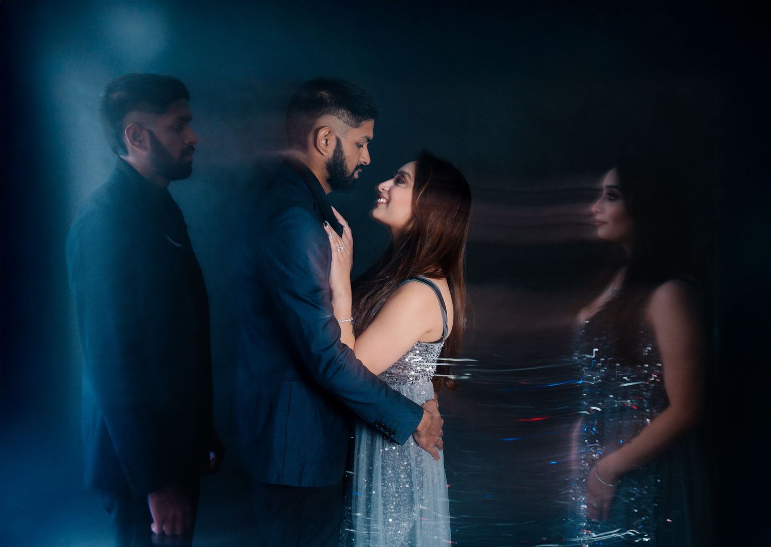 Artistic portrait with reflections of couple in formal attire against dark moody background.
