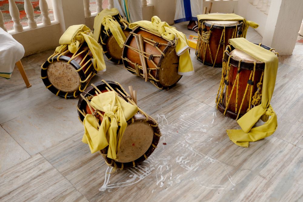 Traditional Indian drums wrapped in yellow cloth arranged on a wooden floor.