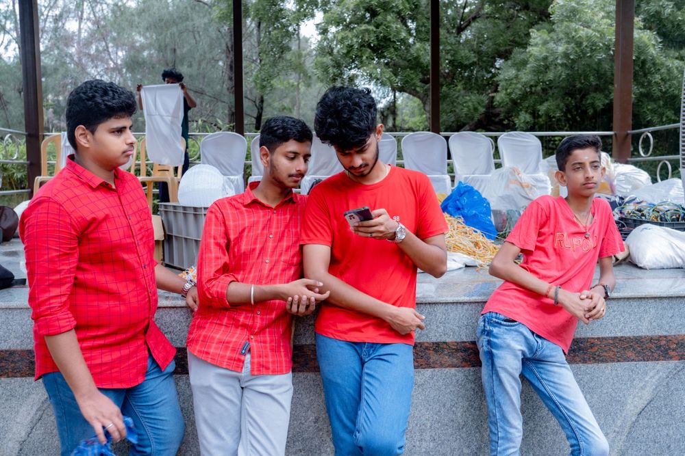 Four young people in red and casual attire looking at their mobile phones.