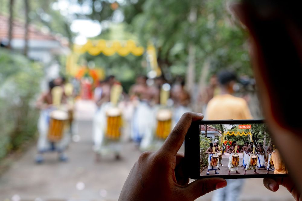 Someone capturing a photo of performers with traditional drums through a smartphone screen.