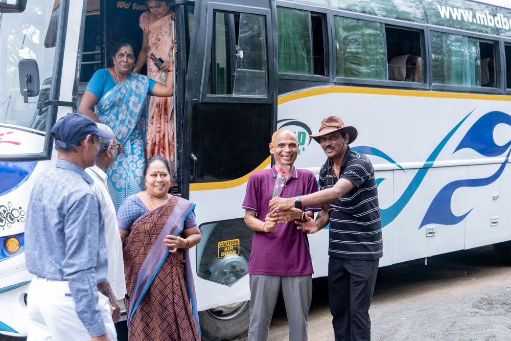 A group of people gathered near a tourist bus during a social occasion.