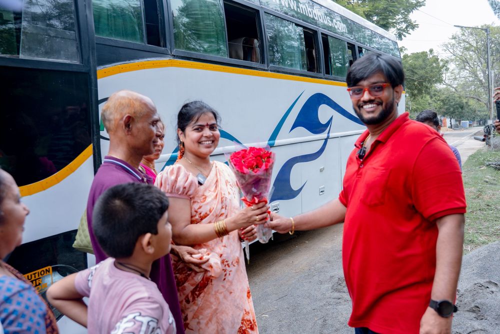 People sharing a light moment near a parked tour bus with blue stripe design.
