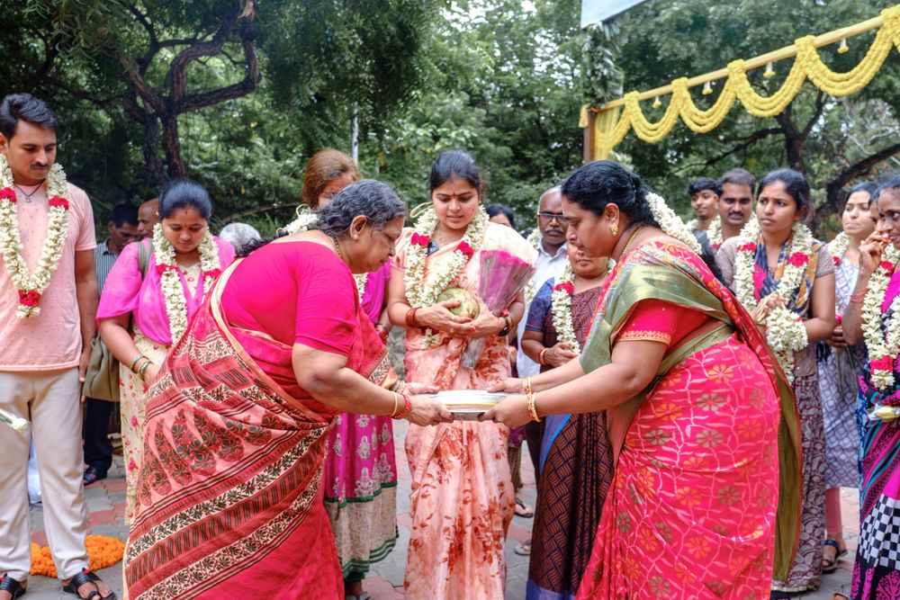Two women in traditional red saris exchanging greetings during a cultural celebration.