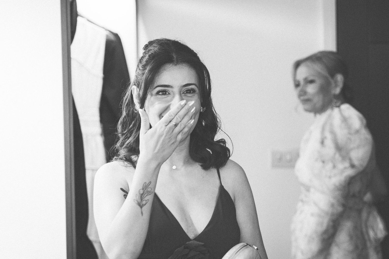 Black and white photo of a woman covering her mouth in surprise, with another woman visible in the background.