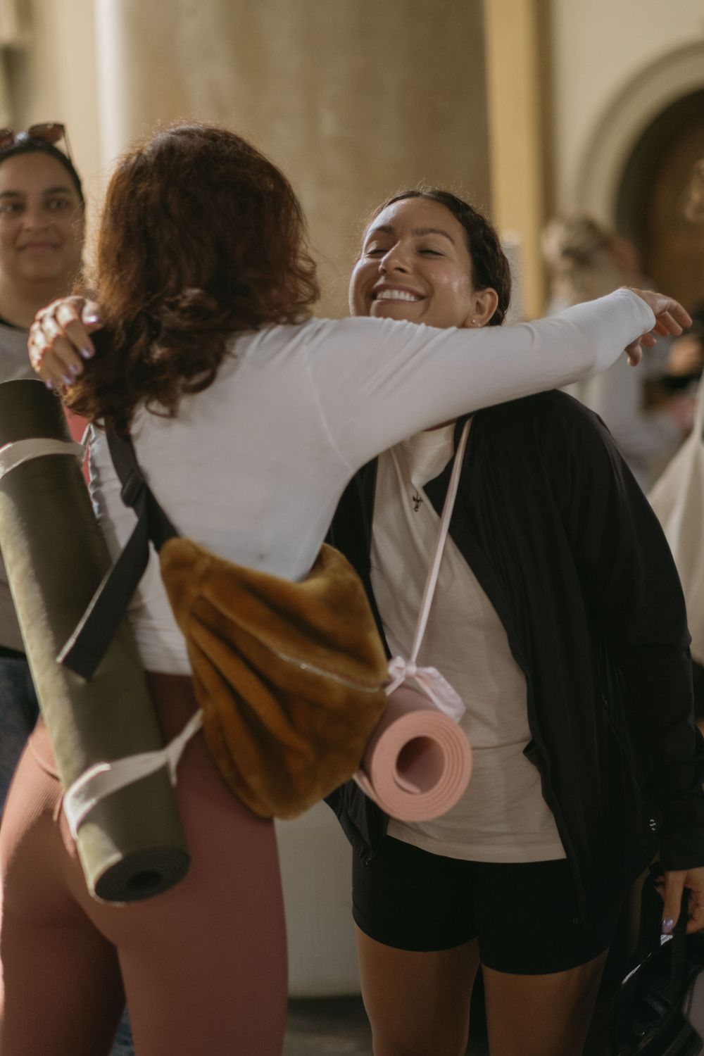 two women hugging and smiling while being captured by yoga event photographer in Stockholm