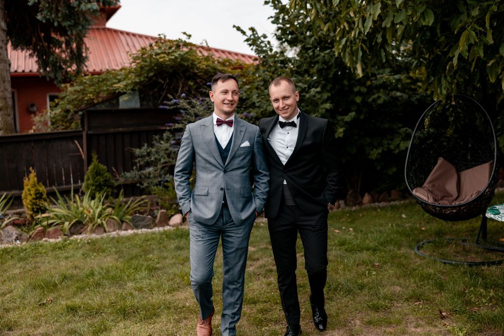 Wedding party members pose casually in a backyard garden setting.