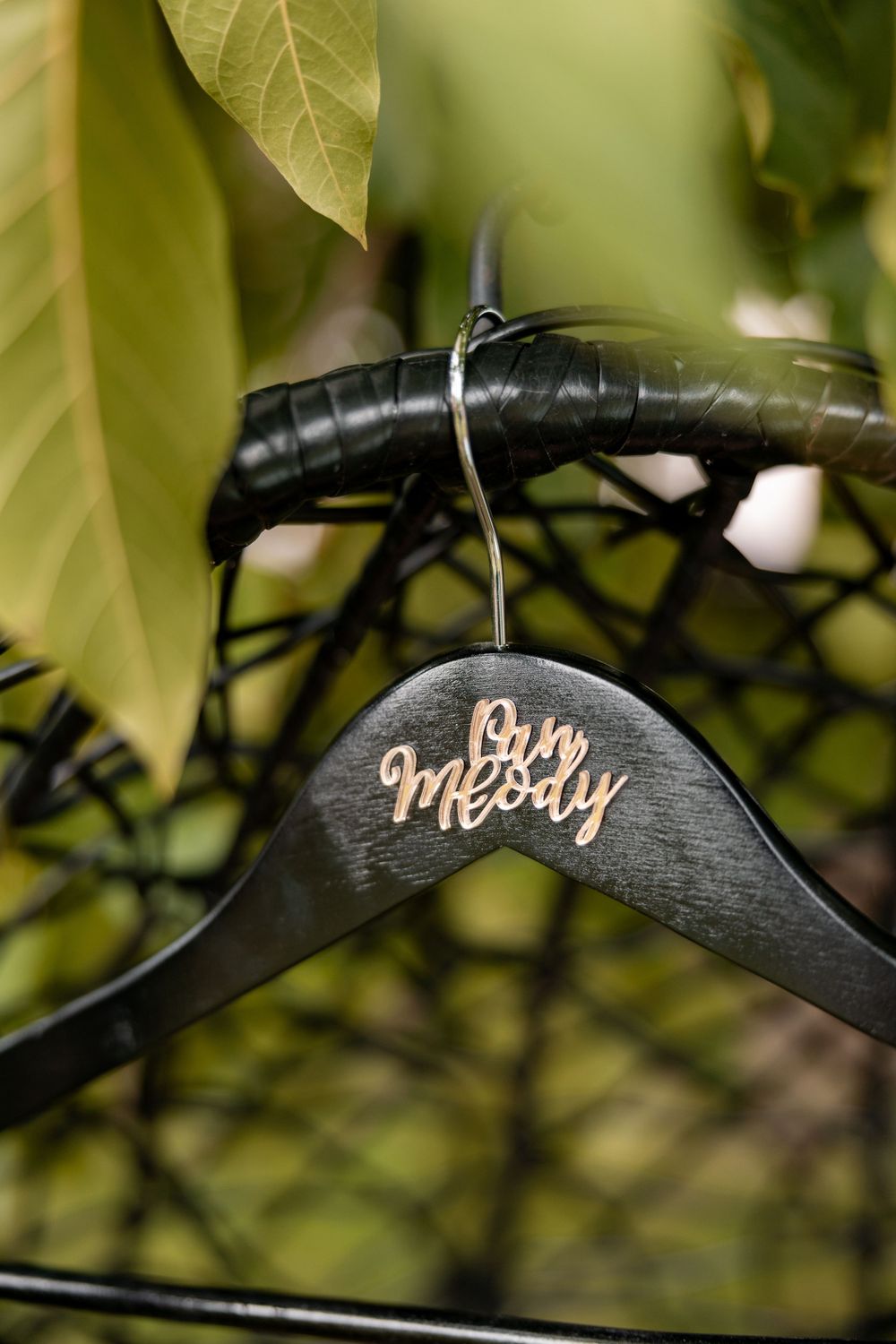Custom wedding dress hanger with Mrs. inscription photographed among green foliage.