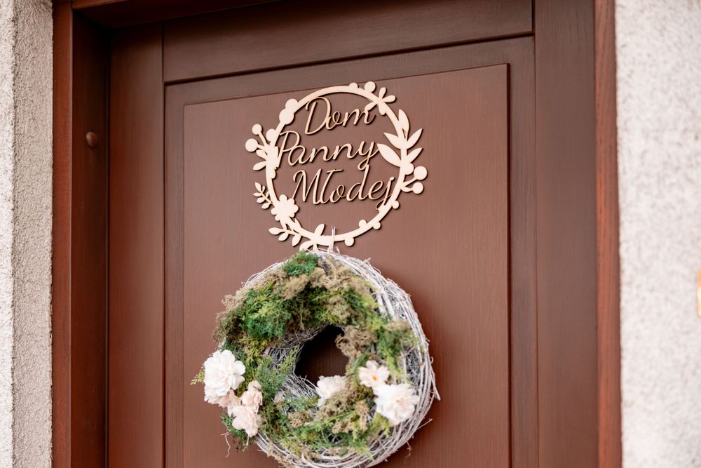 Decorative wedding wreath and welcome sign mounted on a brown door.