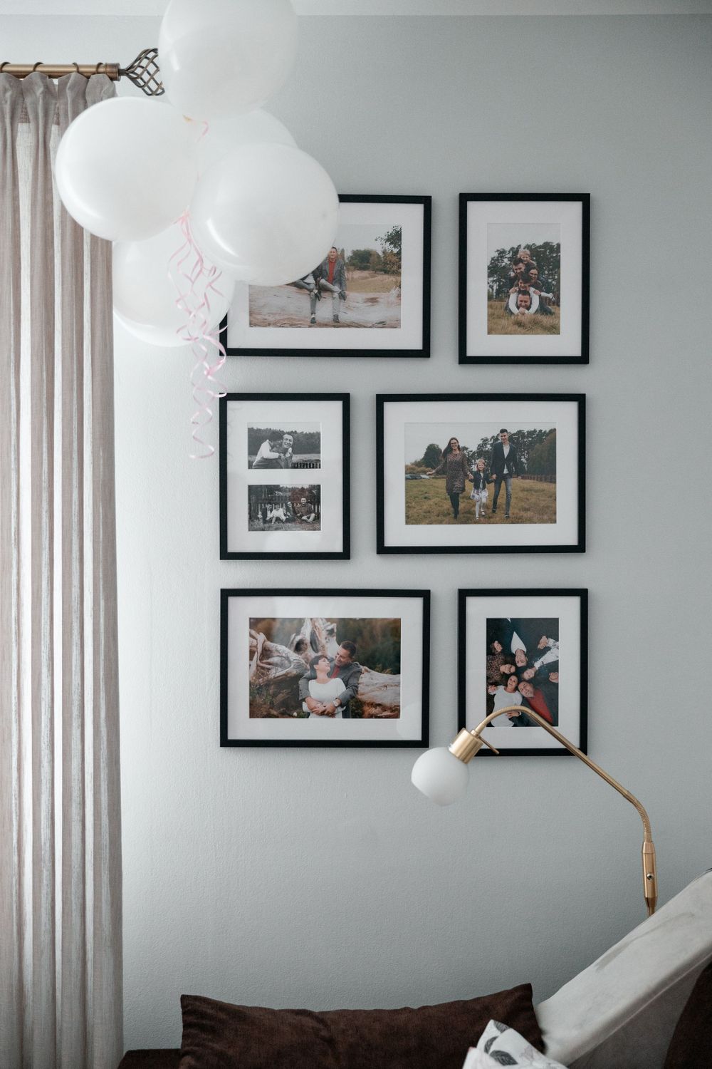 Gallery wall with white balloons featuring black and white family photos in matching frames.