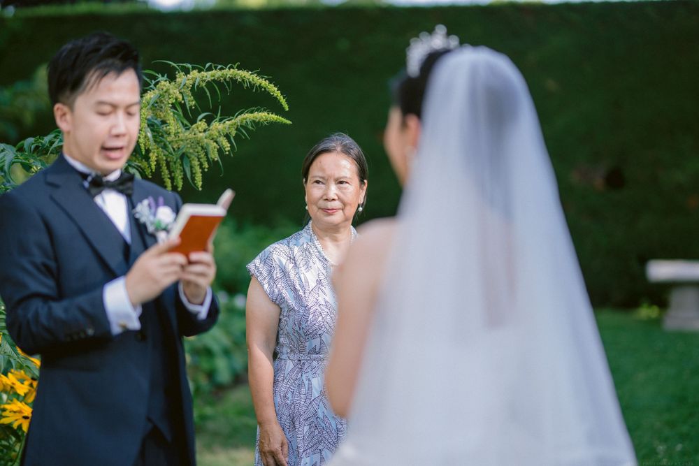 A wedding ceremony moment in a garden setting with guests and floral decorations.