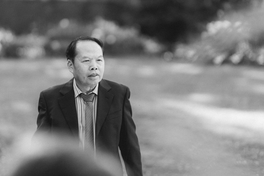 Black and white portrait of a guest speaking during an outdoor wedding event.
