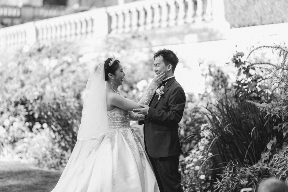 Black and white capture of a tender moment between newlyweds in a garden with ornate balustrade.