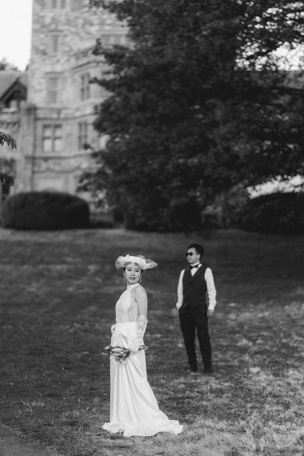 Classic black and white wedding photo with couple posing on castle grounds.