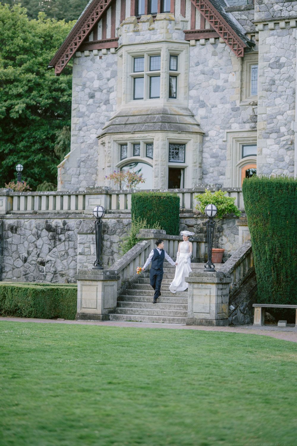 Wedding couple descending grand stone staircase of Gothic revival castle.