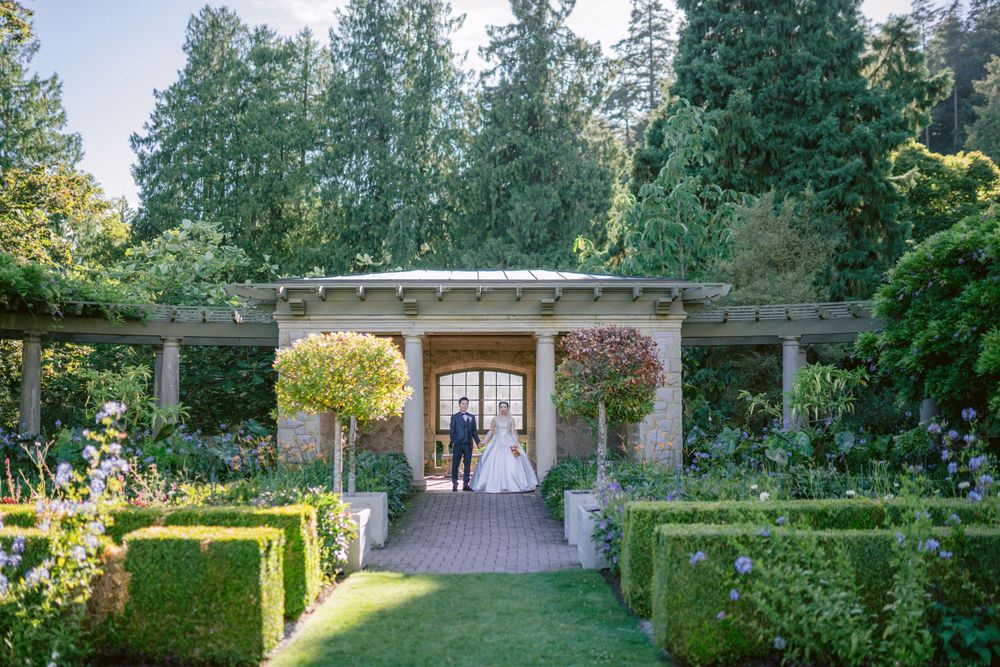 Garden archway with climbing plants frames couple at end of formal garden path.
