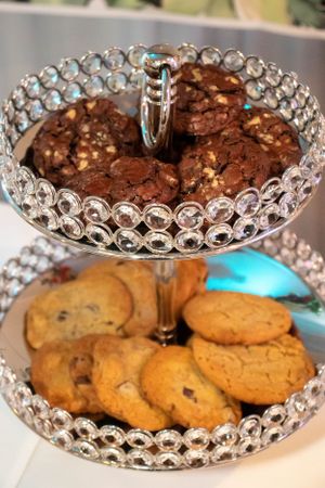 Crystal cake stands displaying chocolate brownies and golden cookies at a dessert table.