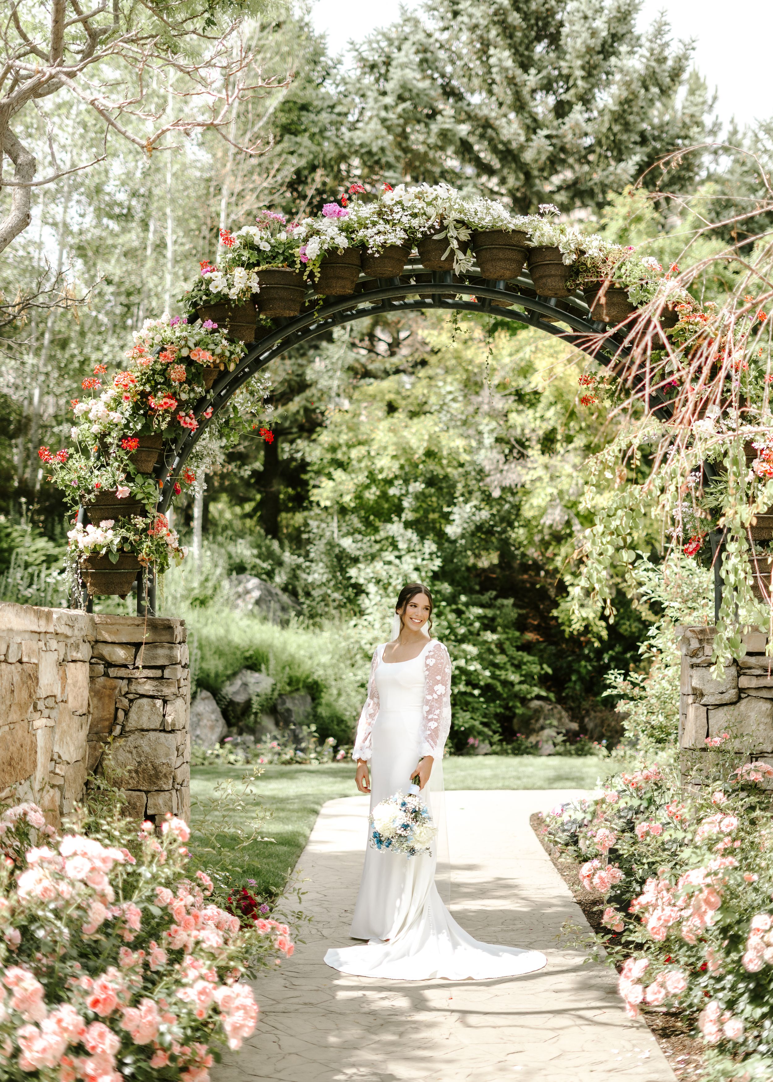 Stone archway covered in climbing roses and flowers creates romantic garden wedding setting.