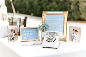Vintage-style wedding decor display with framed signs, photographs and retro white telephone.