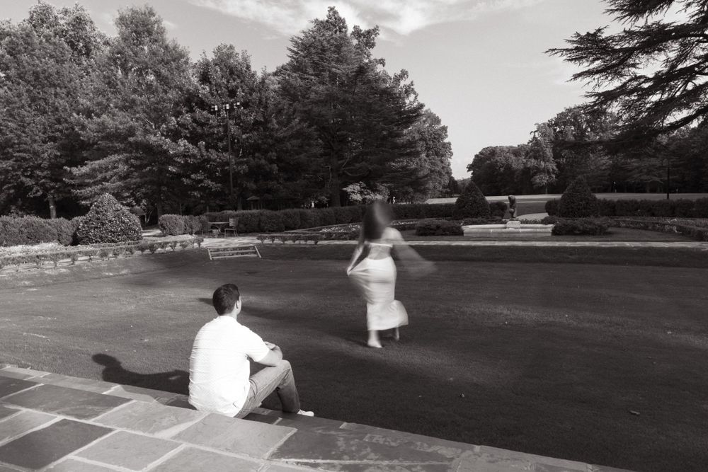 Couple dancing together on an outdoor patio surrounded by trees and stone walls.