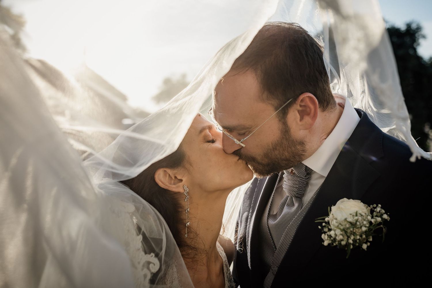 A romantic wedding moment captured with flowing veil in sunlight.