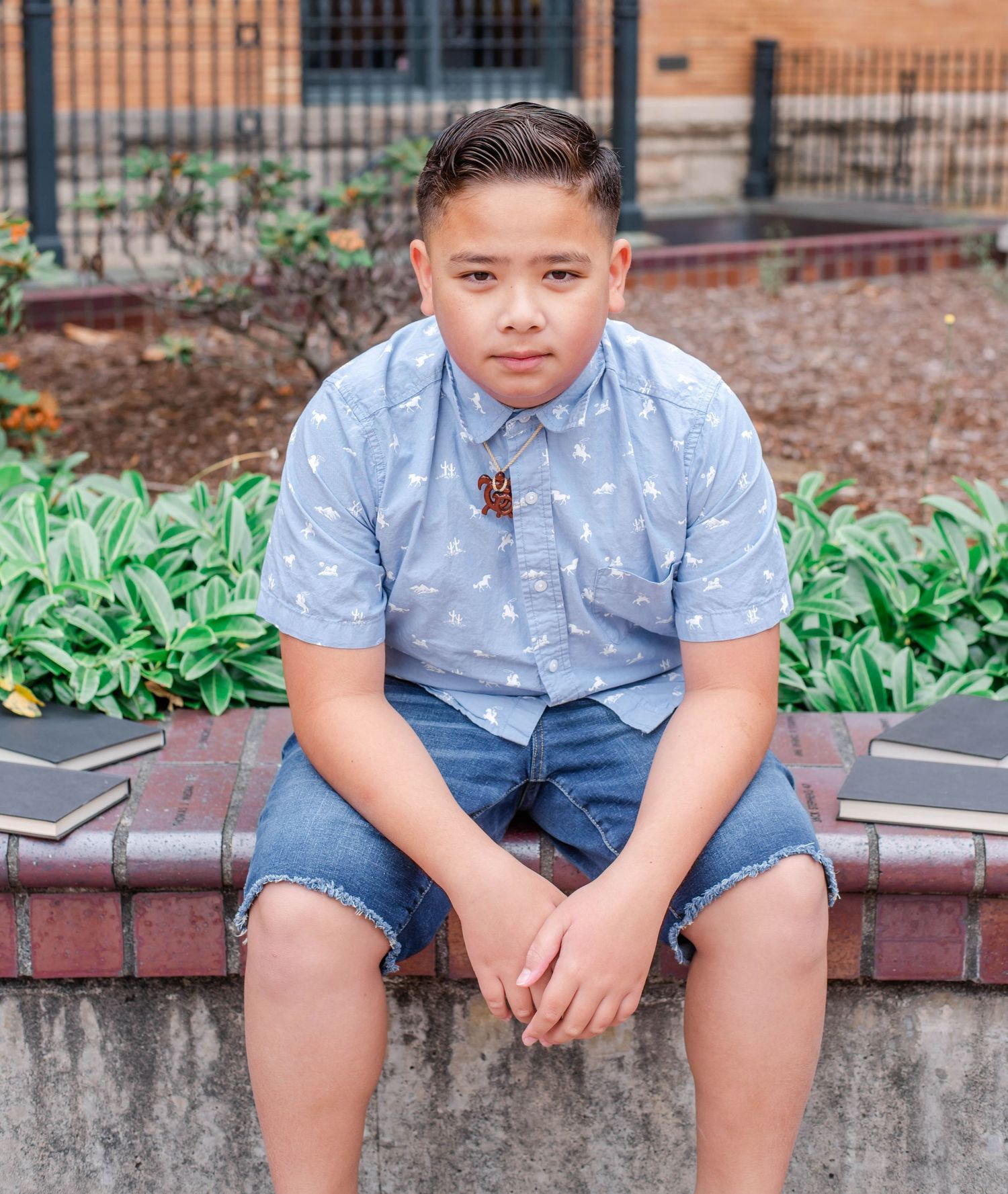 Casual outdoor portrait session featuring someone in a light blue button-down shirt and denim shorts sitting on brick steps.