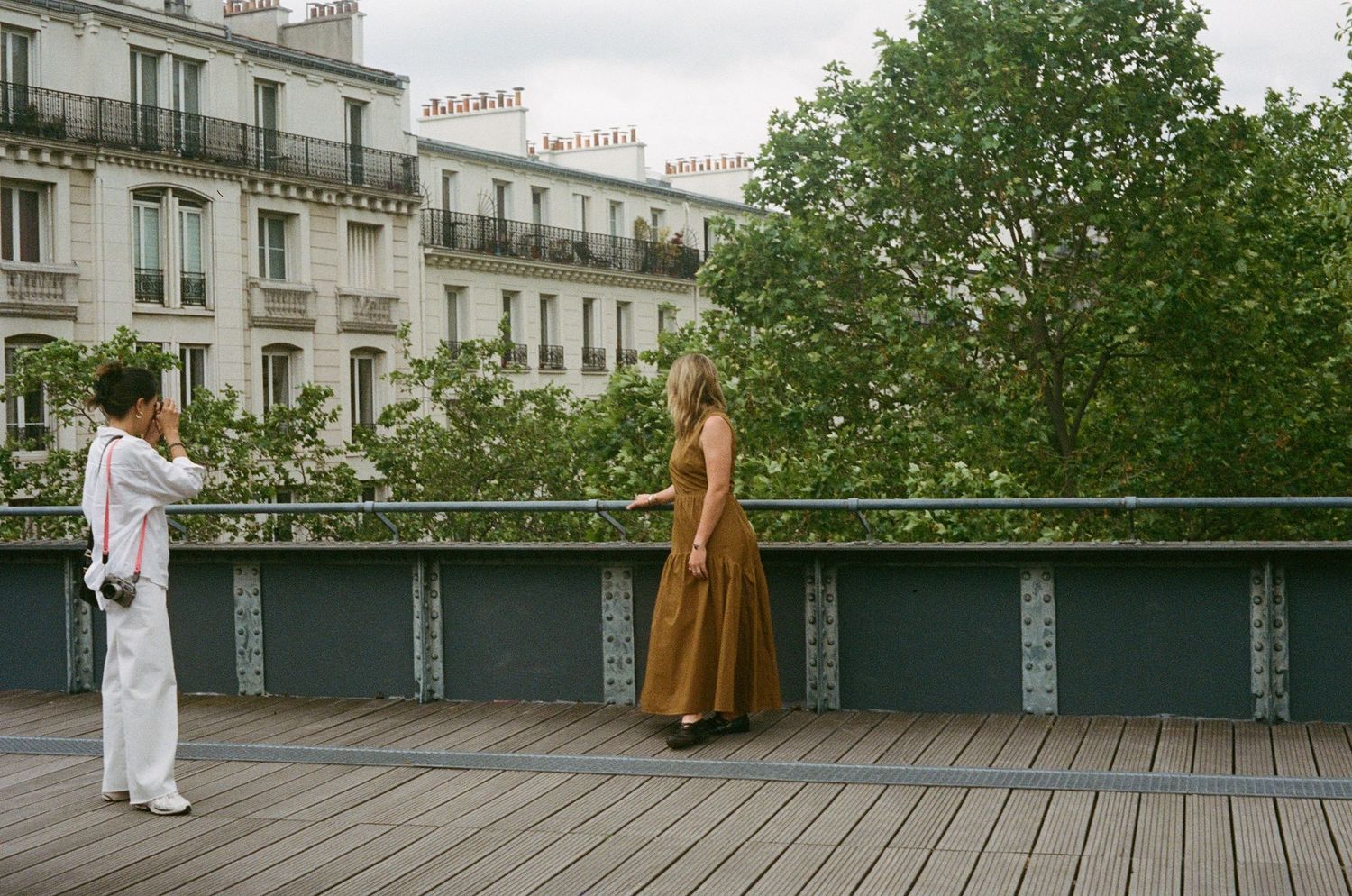 lifestyle portrait photographer with elevated, destination feel and natural light. photographer and subject on bridge in Paris France