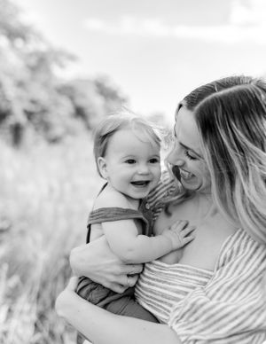 A tender moment between parent and child outdoors captured in black and white photography.