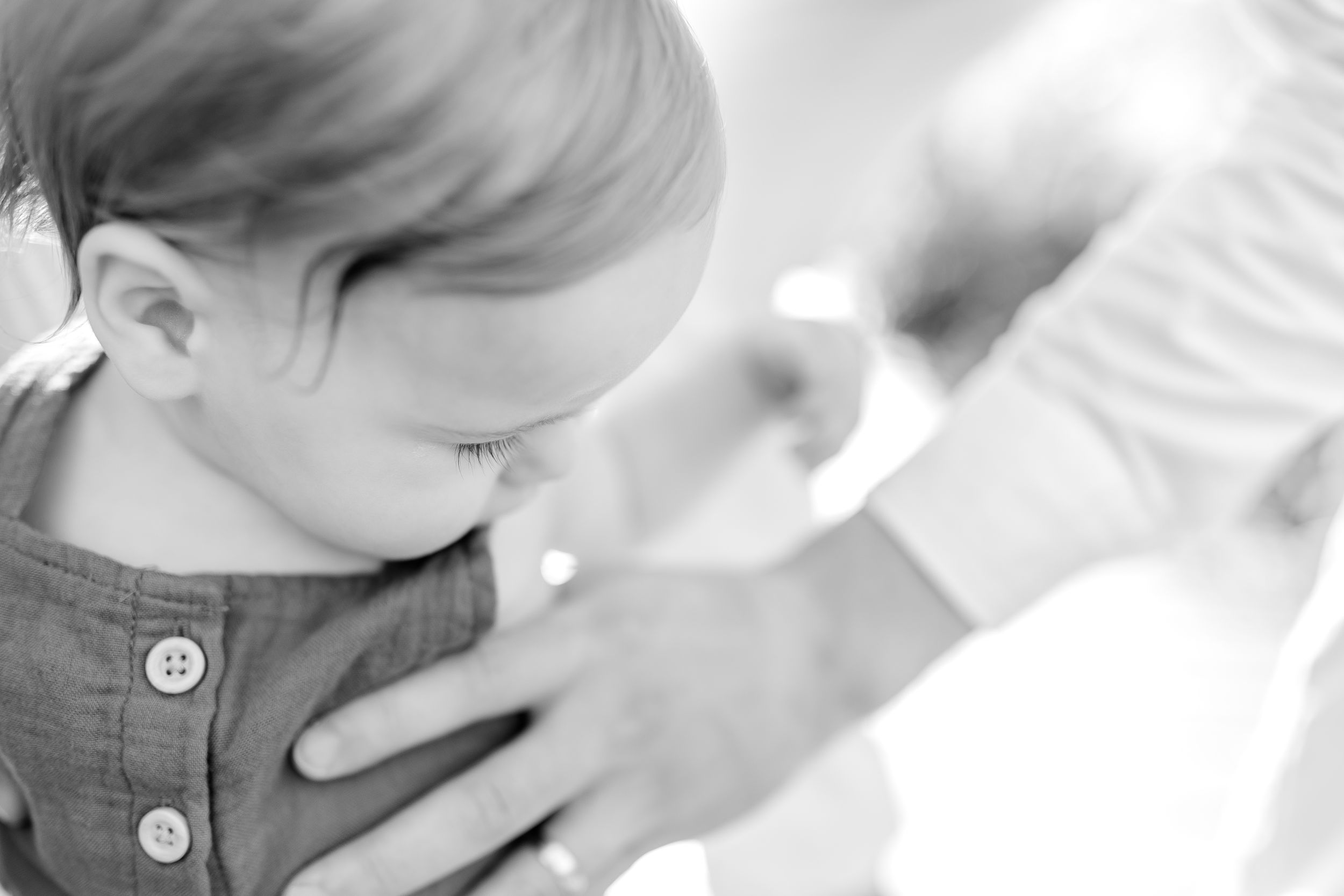 Black and white close-up photograph capturing gentle parental touch.