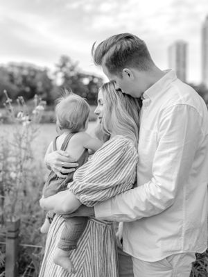 Outdoor family portrait with city skyline visible in the soft background.