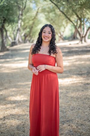 Beautiful red maxi dress showcased in an outdoor woodland setting with dappled sunlight filtering through the trees.