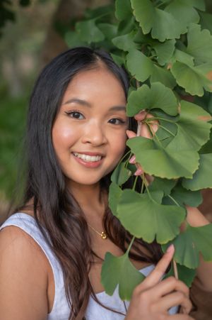 Close-up portrait amongst green ginkgo leaves showing natural beauty and summer style.