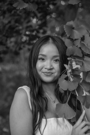 Black and white portrait by ginkgo leaves captures artistic natural lighting and elegant pose.