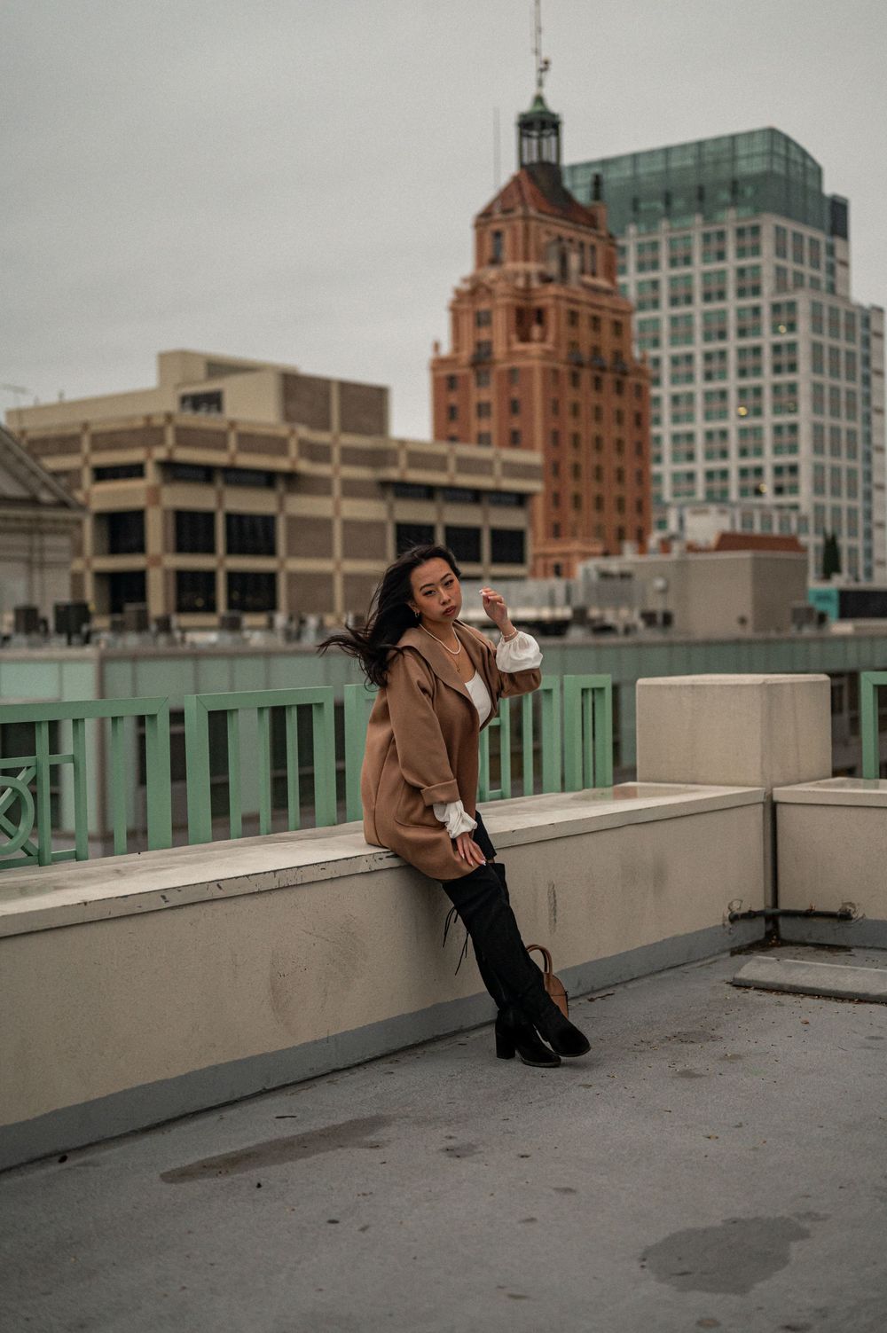 A rooftop fashion portrait with historic brick buildings in the background.