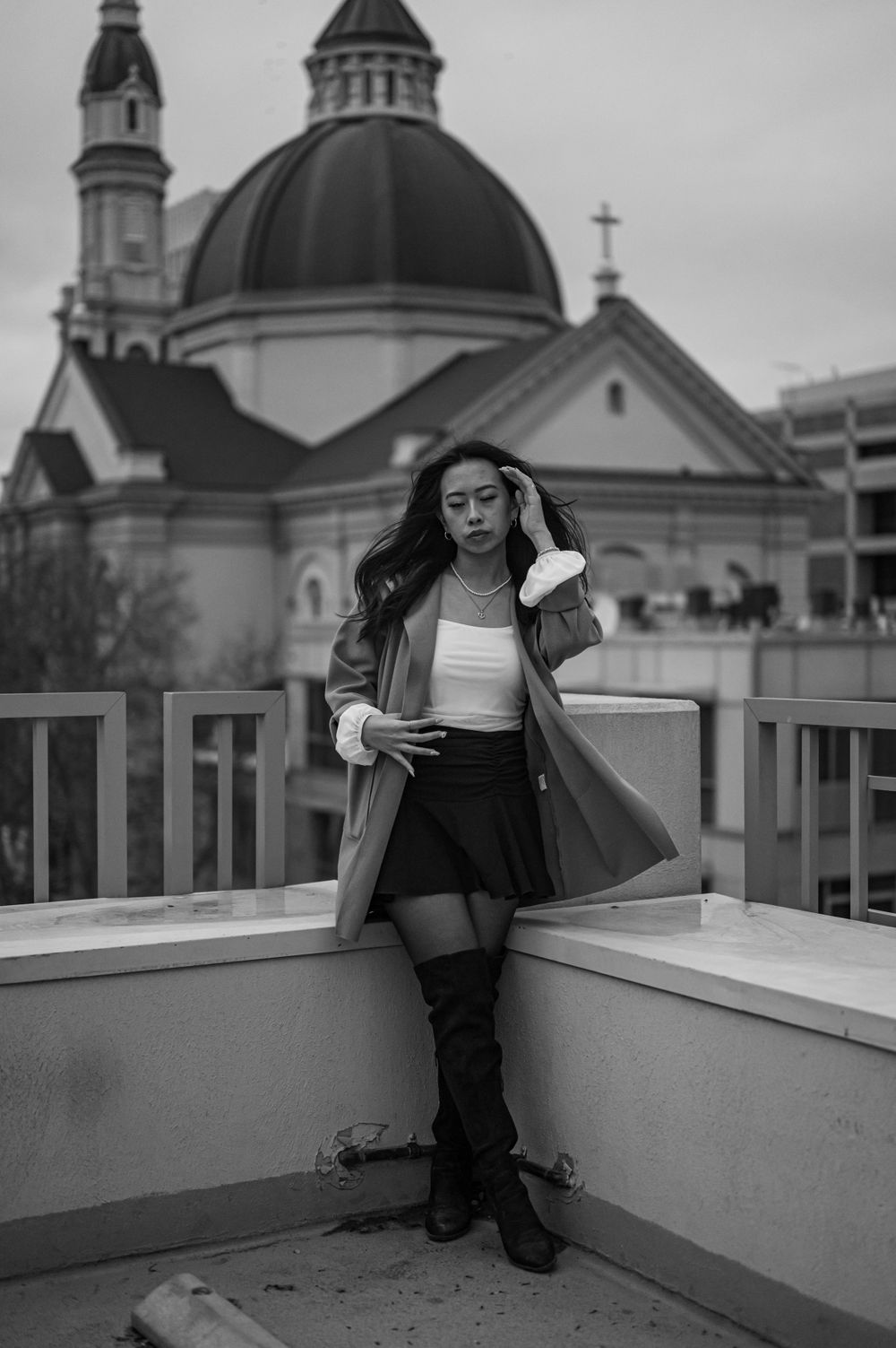 A stylish urban portrait against a domed church with a person in a long coat and boots.