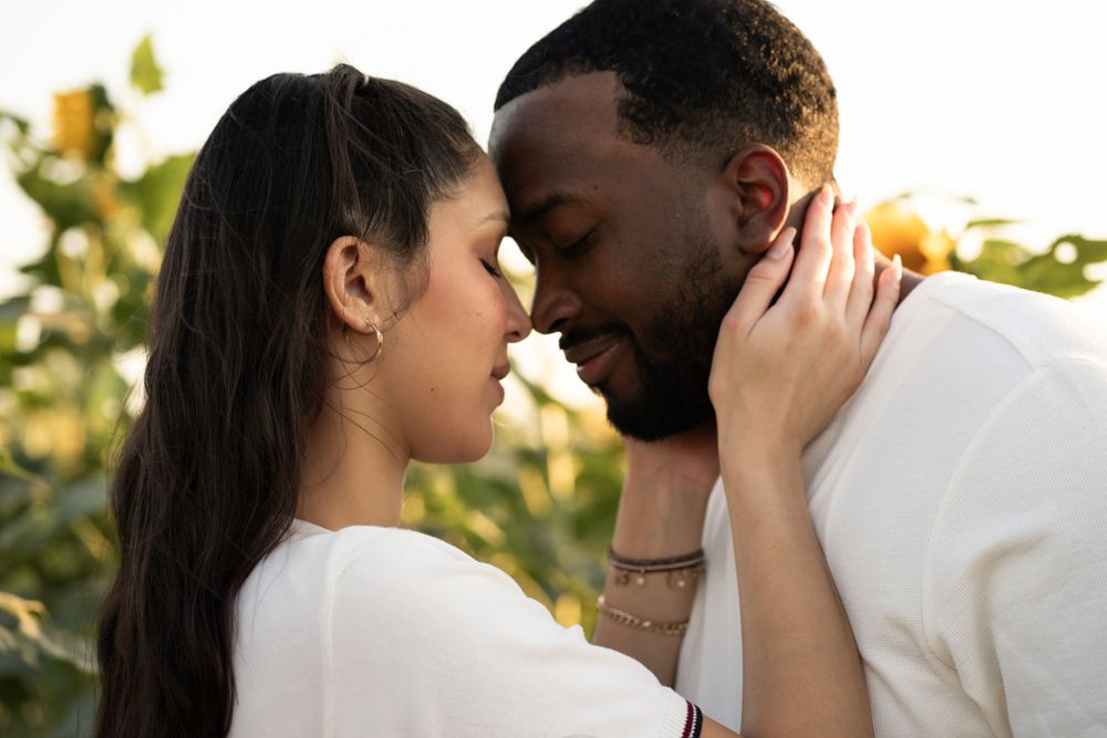 Romantic couple sharing intimate moments in a garden setting with golden sunlit background.