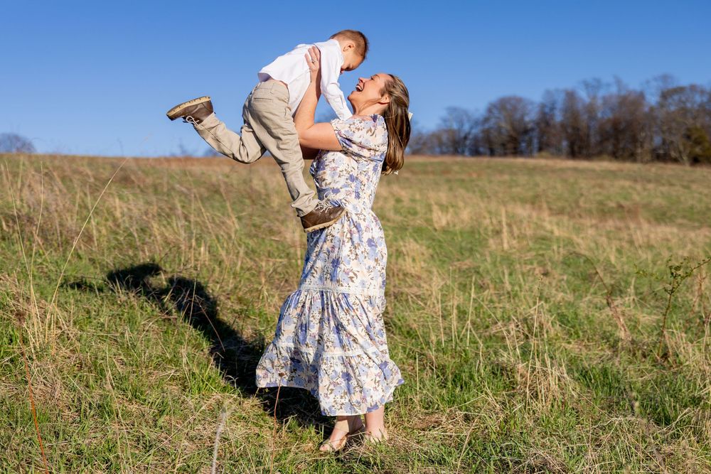 Two people share a tender moment in a sunlit meadow while wearing country-style attire on a bright autumn day.