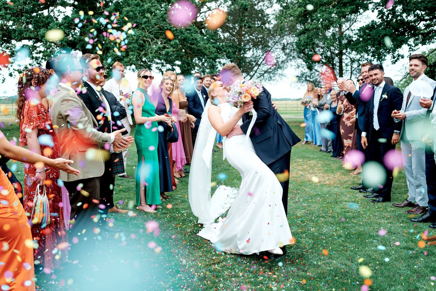 Guests create a celebratory exit path for newlyweds walking through flower petals.