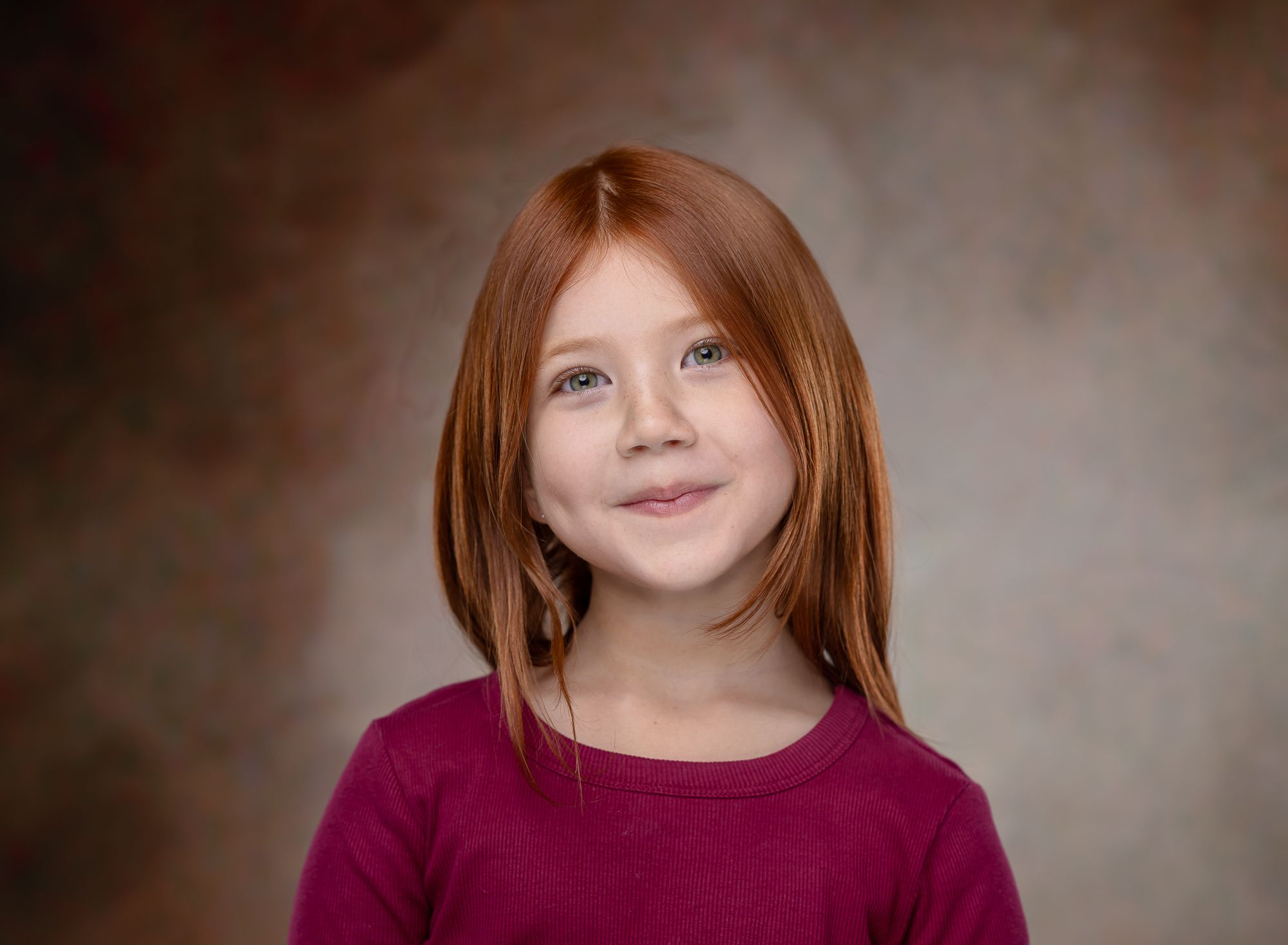 Studio portrait featuring a person in a maroon top against a dark backdrop.