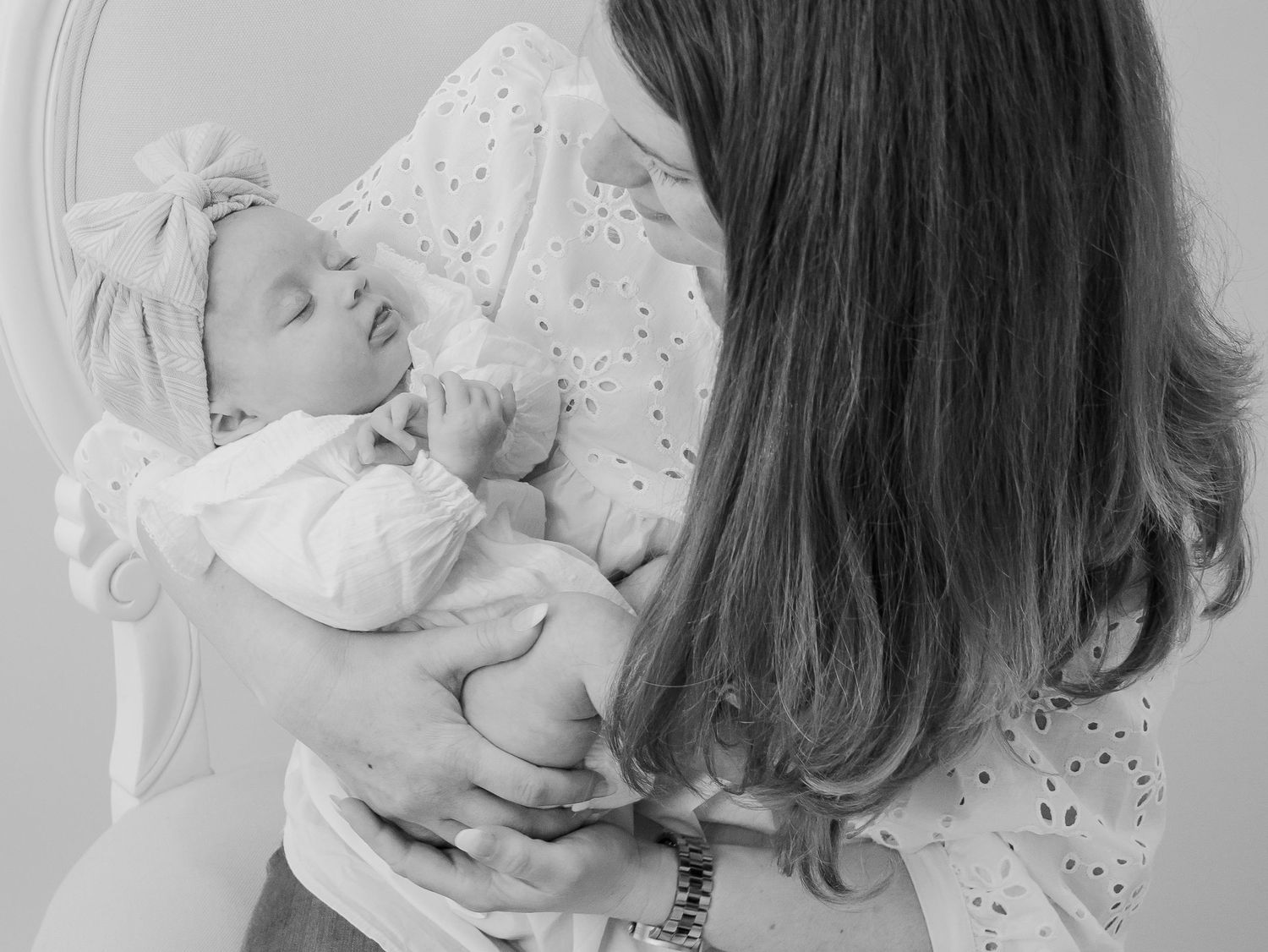 A tender black and white moment showing a baby cradled in someone's arms.
