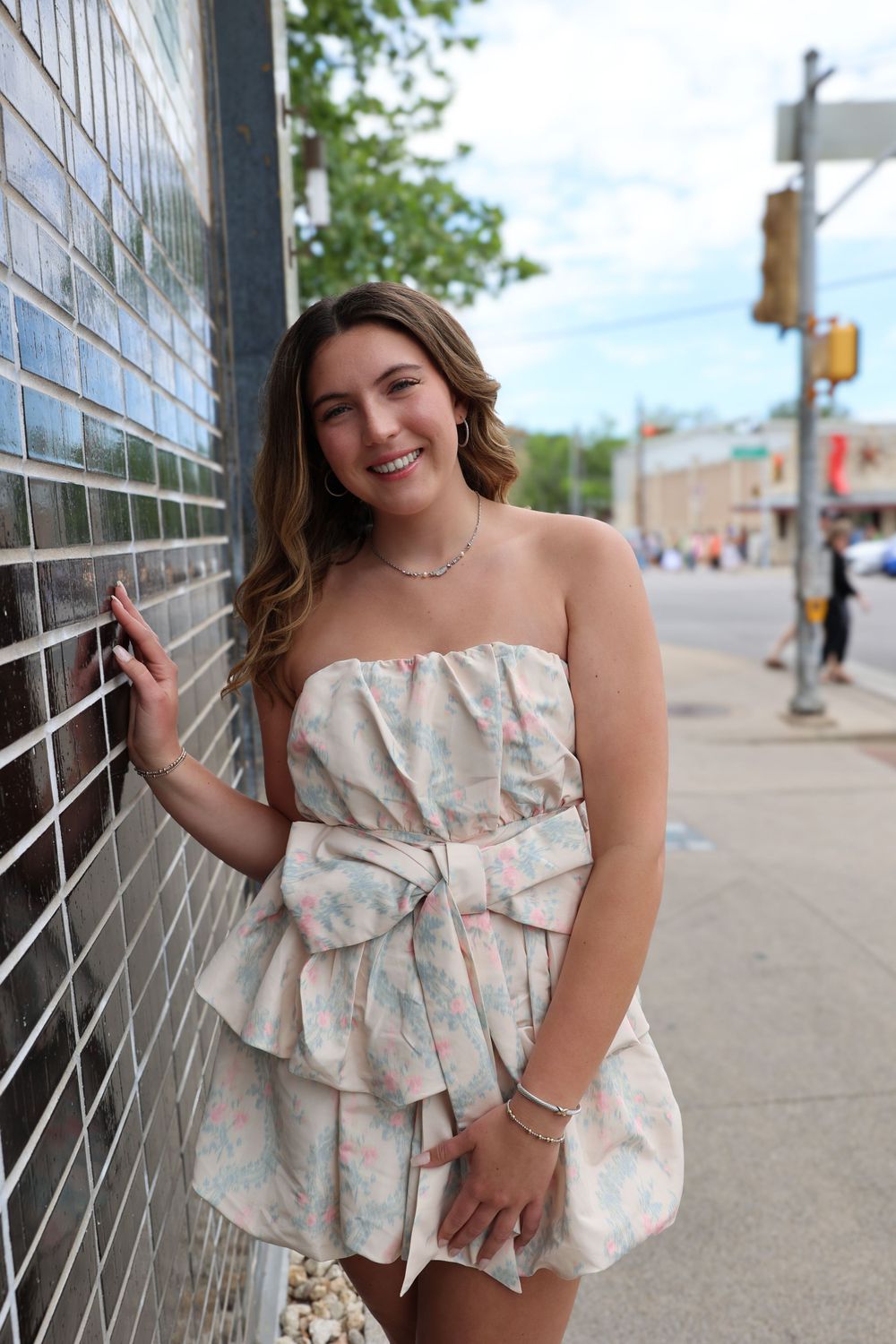 Street style photo featuring a floral strapless mini dress with bow detail in an urban setting.
