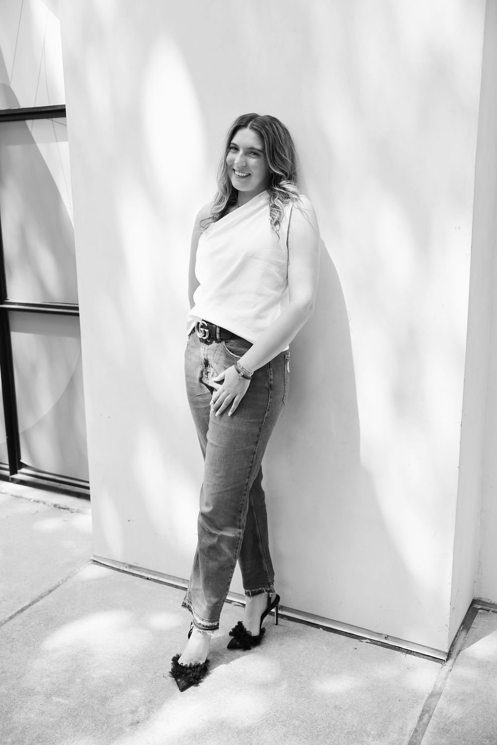 Black and white fashion photo showing classic denim and white sweater combo against white wall.