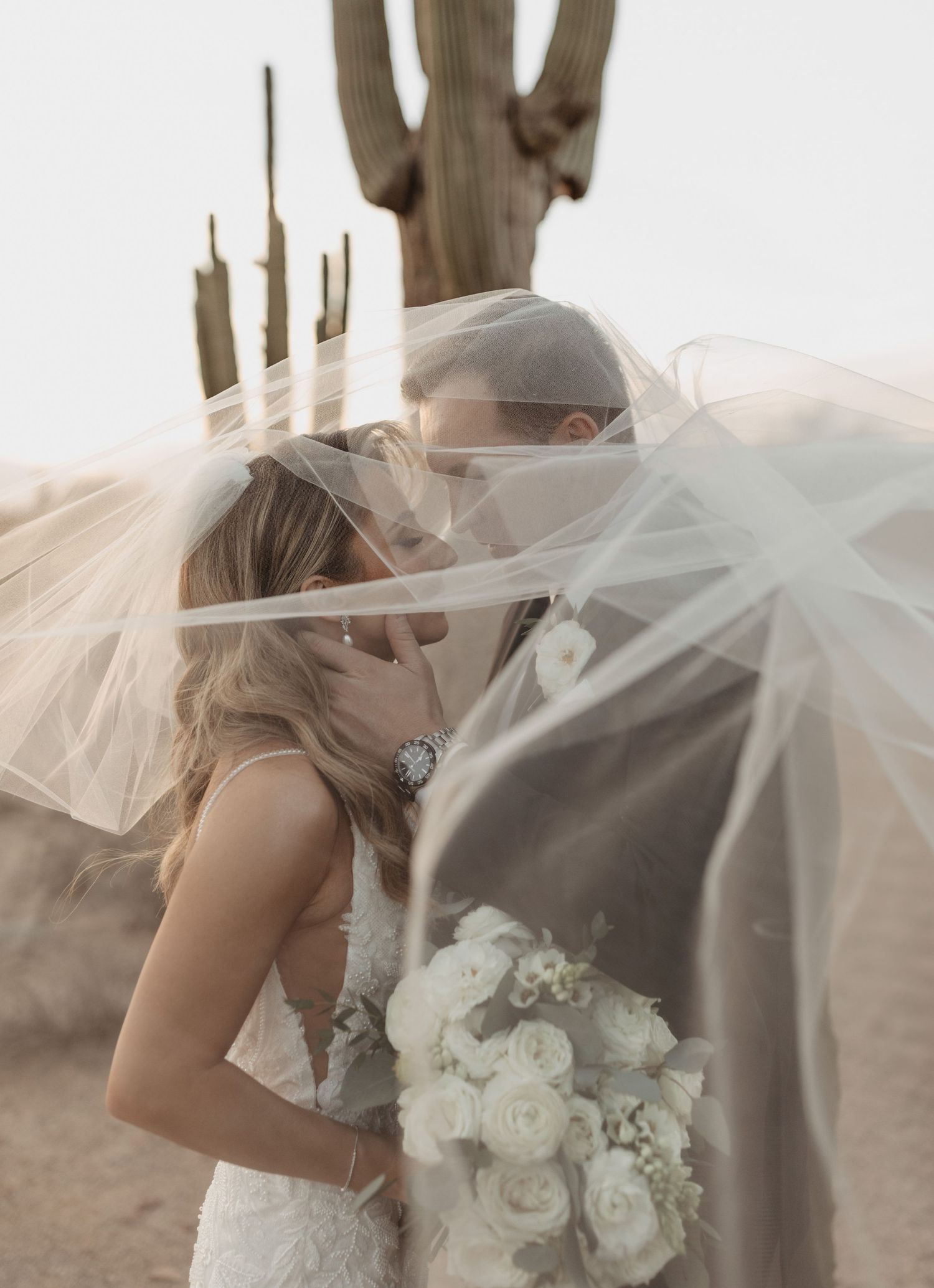 Romantic wedding photo with flowing veil and white bouquet in soft lighting. Arizona wedding photographer. Desert bridal session.