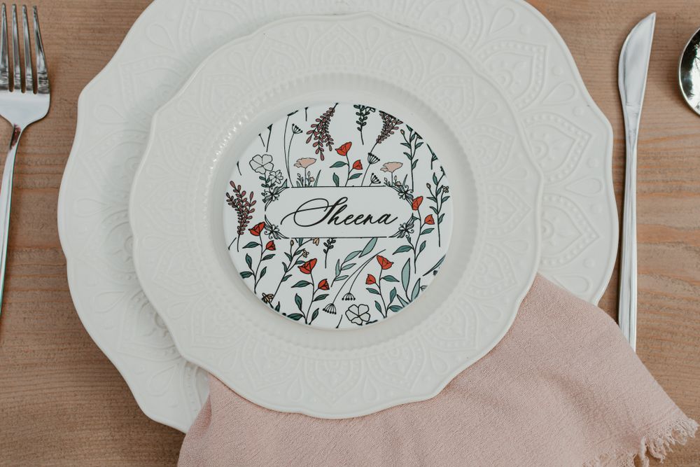 Elegant place setting with decorative china plates and floral designs on a wooden table.