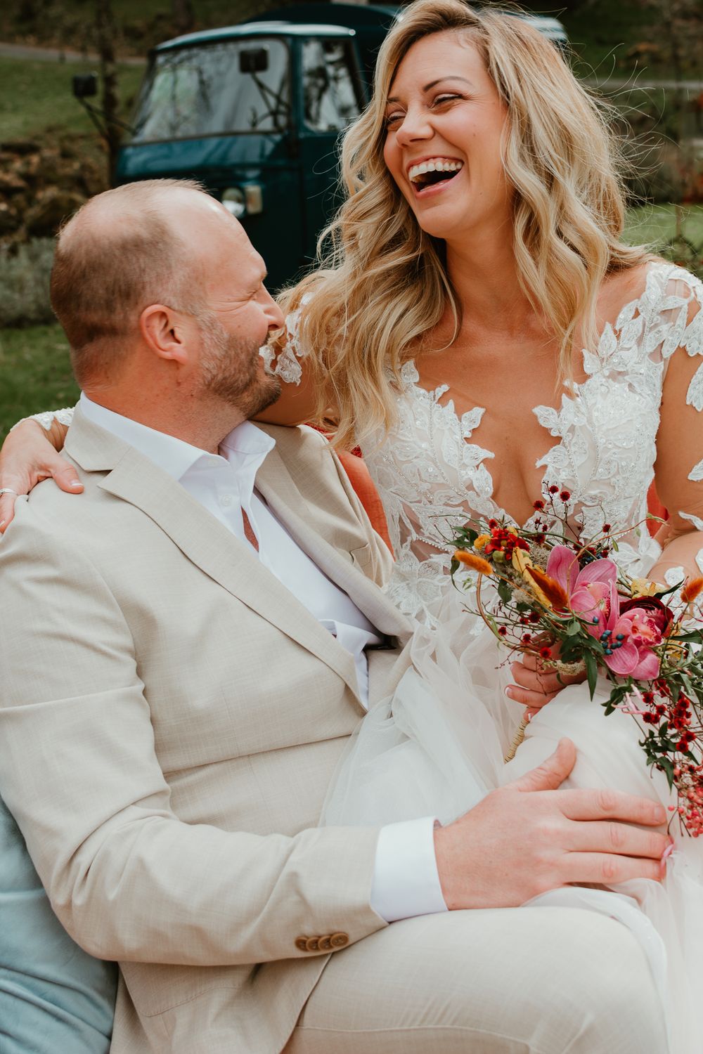 A romantic wedding photoshoot with a couple in cream and white attire holding a colorful bouquet.